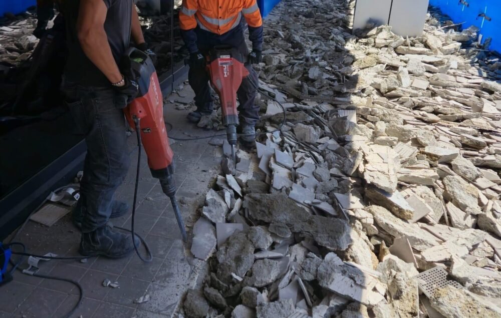 Demolition workers use jackhammers to break up concrete for removal